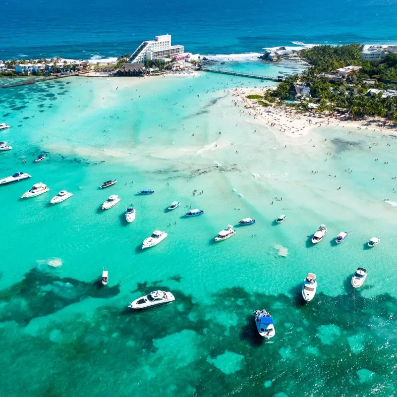 Isla mujeres beach front with pleasure boats and a resort in the background