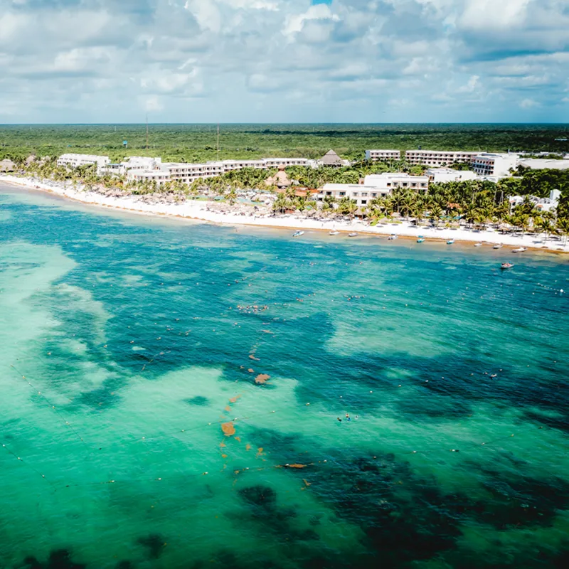 Aerial view of Akumal, with boats, resorts, and jungle in the background