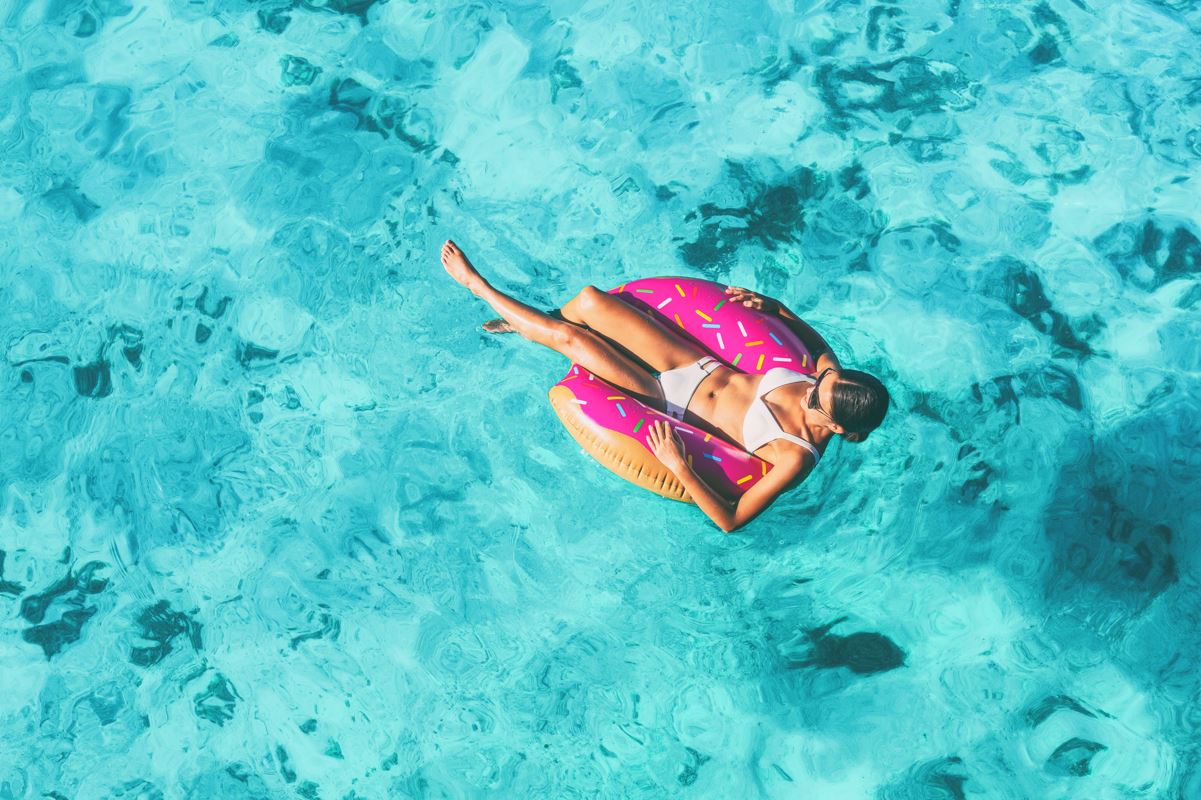 A woman floating on a doughnut inflatable in clear blue water