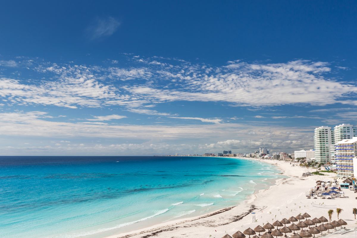a panoramic view of the coastline in cancun with resorts and beach palapas