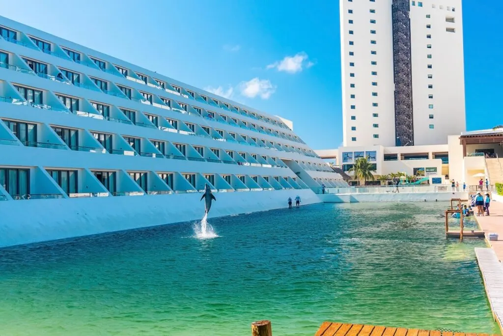 Dolphin jumping midair in big swimming pool of a luxury hotel building