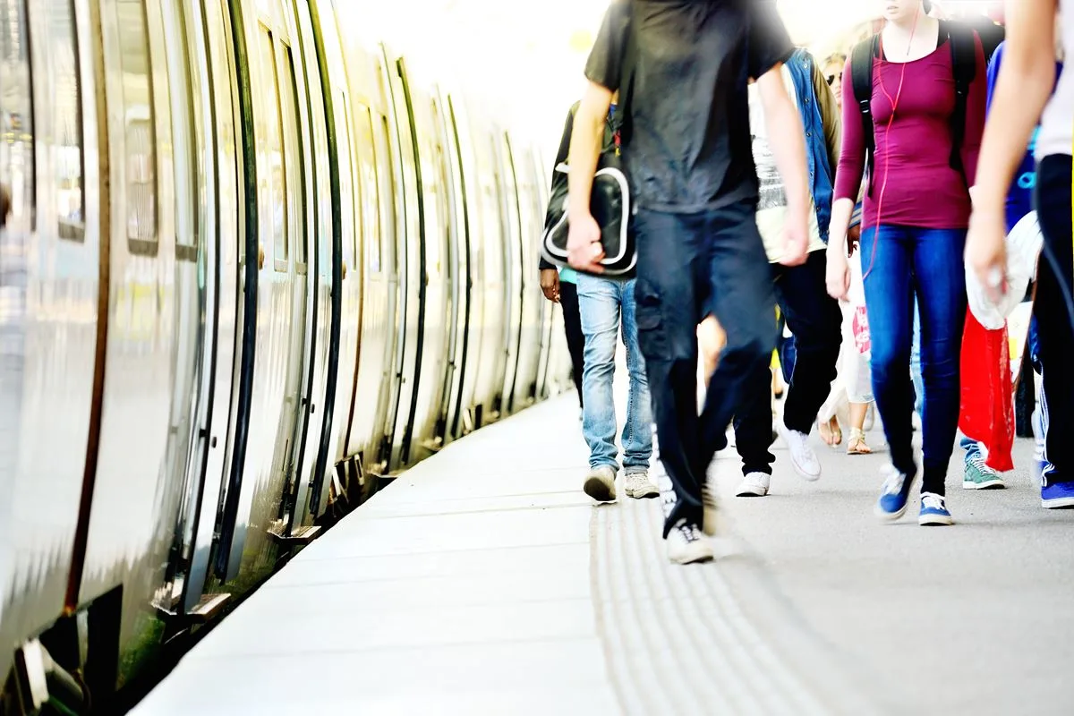 Passengers walking on train station by a stationary train