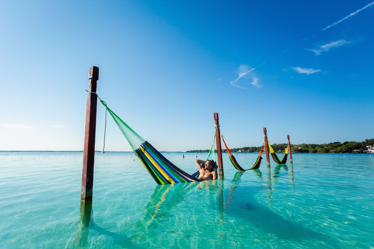 A man on a hammock in the water of bacalar lagoon