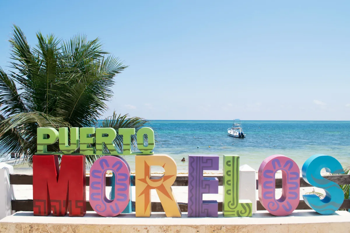 Boat Drifting in the Water Behind the Puerto Morelos Sign