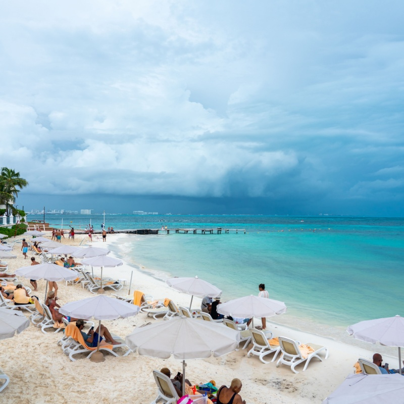a white sand beach in cancun with stormy weather
