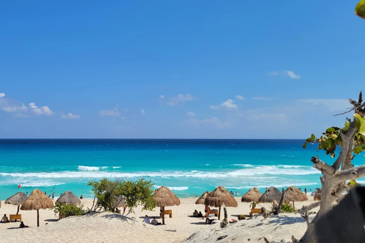 stretch of pristine beach in Cancun with beach umbrellas and crystal blue waters