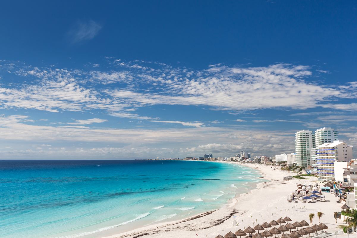 a panoramic views of the cancun hotel zone beach with multiple resorts in view