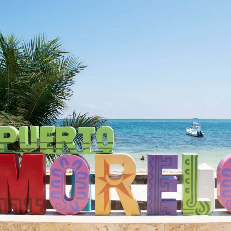 Boat Drifting in the Water Behind the Puerto Morelos Sign