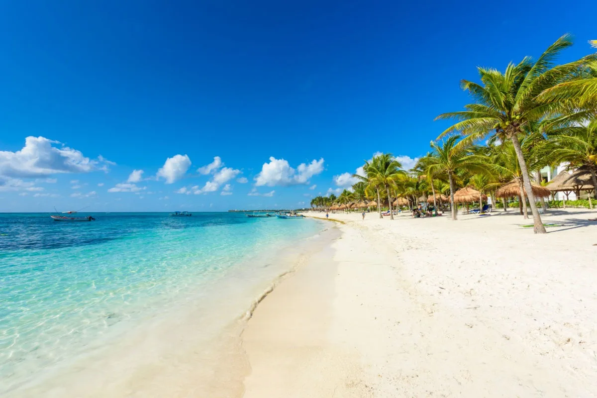 a white sand beach in cancun with few travelers and blue water