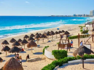 Tourists and Palapas on a Beach in Cancun, Mexico