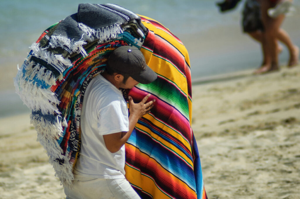 Vendor Selling Colorful Blankets on a Beach