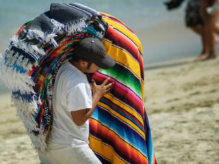 Vendor Selling Colorful Blankets on a Beach