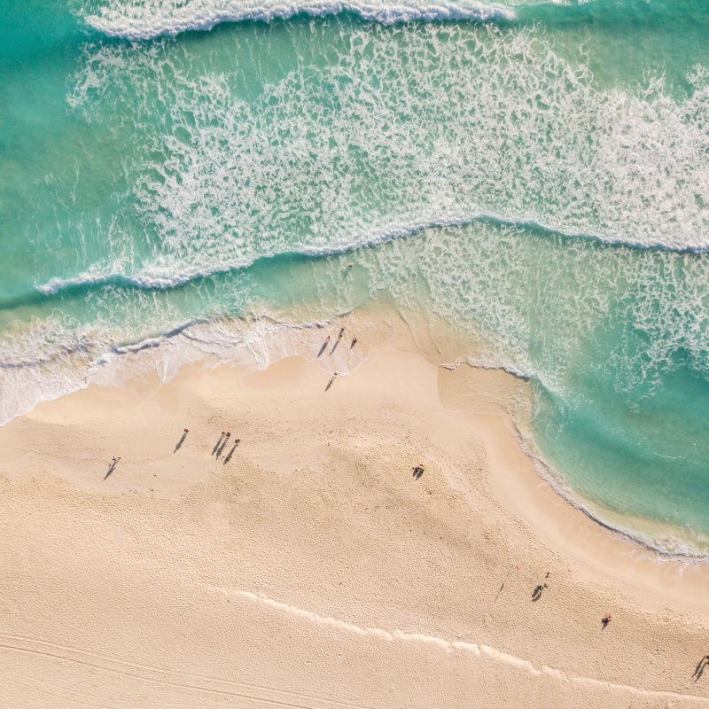 aerial view of a white sand beach in cancun with waves