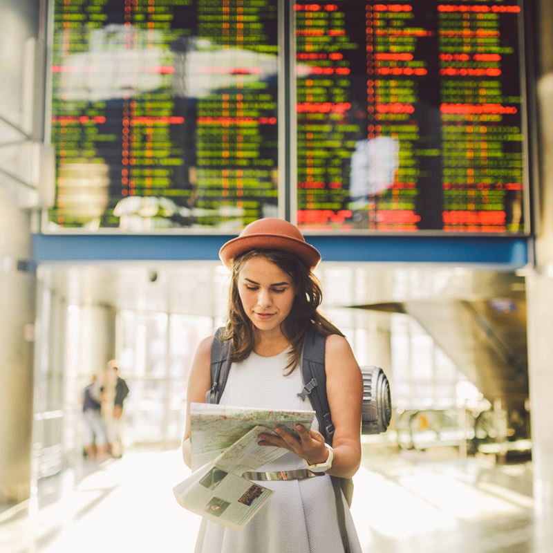Young tourist girl looking at map at train station
