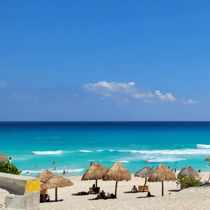 stretch of pristine beach in Cancun with beach umbrellas and crystal blue waters