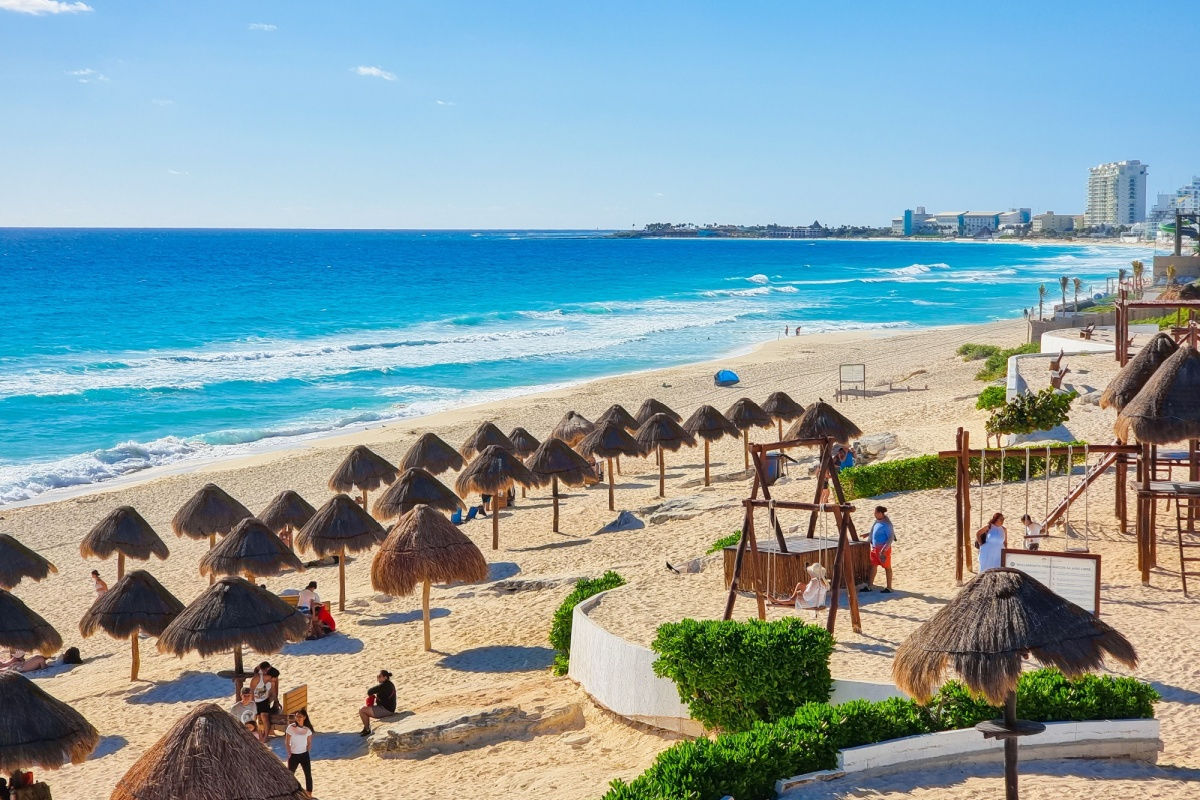 a popular white sand beach in cancun with parasols