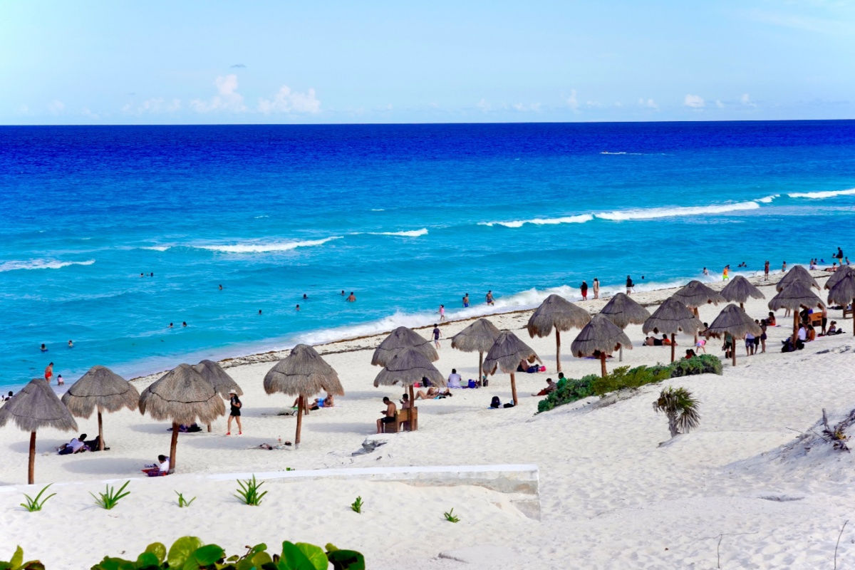 a white sand beach in cancun with travelers in summer