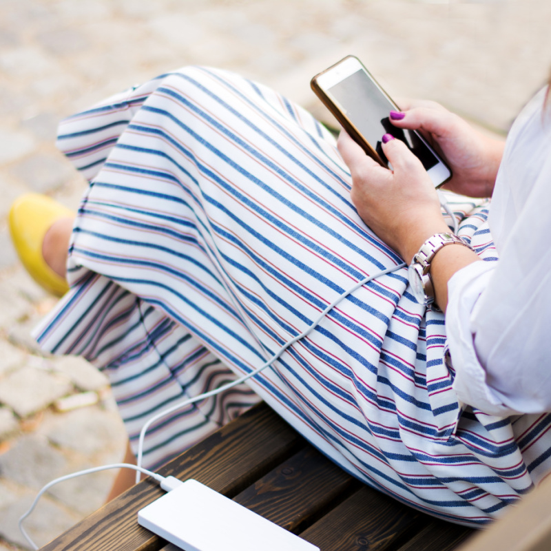 Woman Charging a Phone on a Charging Bank