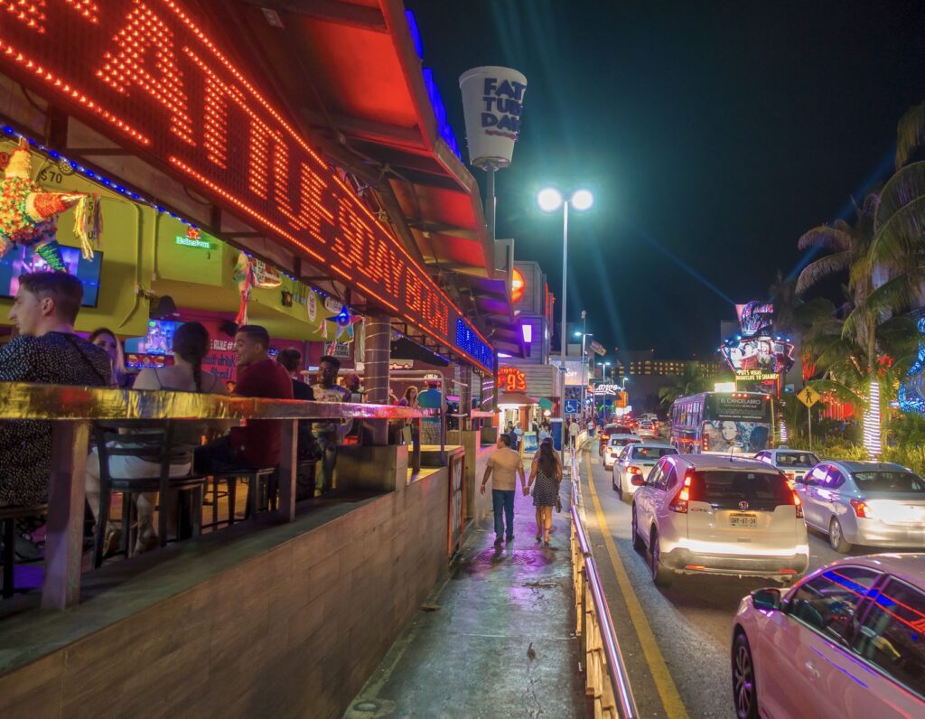 Tourists walk down street at night in Hotel Zone
