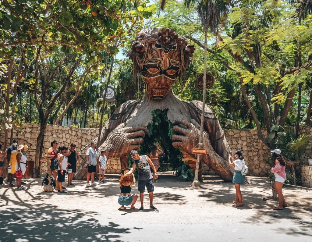 Tourist beachgoers photographing in front of Ven a La luz sculpture installed at the resort Ahau