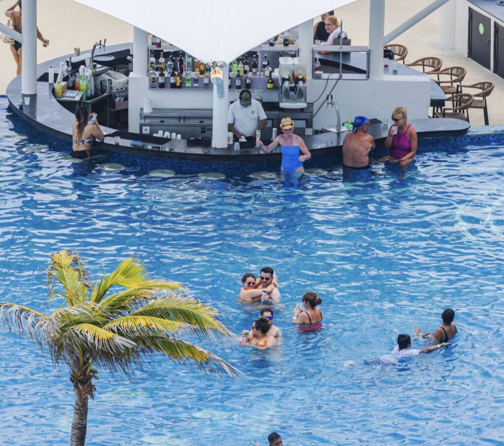 Resort swimming pool with swim-up bar and people relaxing in water. Mexico. Cancun.