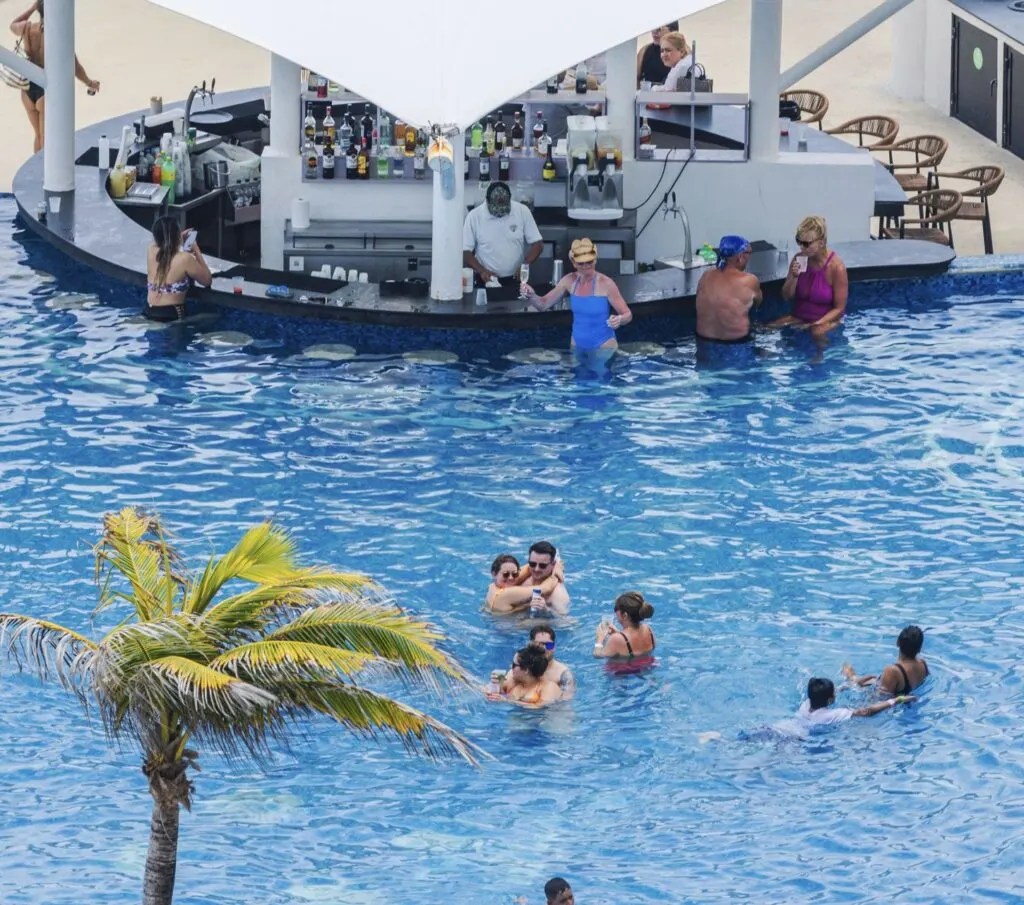 Resort swimming pool with swim-up bar and people relaxing in water. Mexico. Cancun.