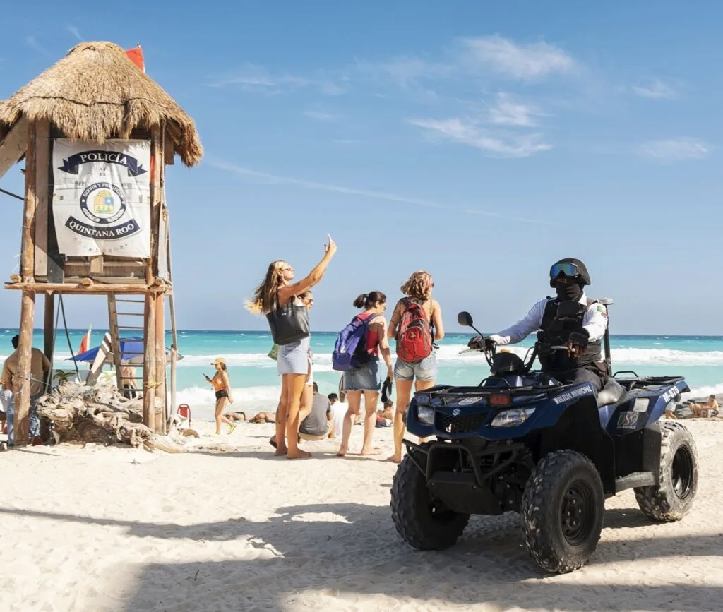 Police officer on Cancun beach on ATV with tourists waving
