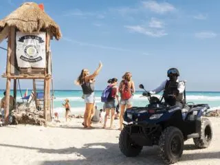 Police officer on Cancun beach on ATV with tourists waving