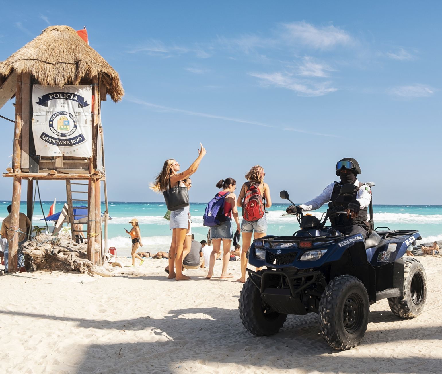 Police officer on Cancun beach on ATV with tourists waving