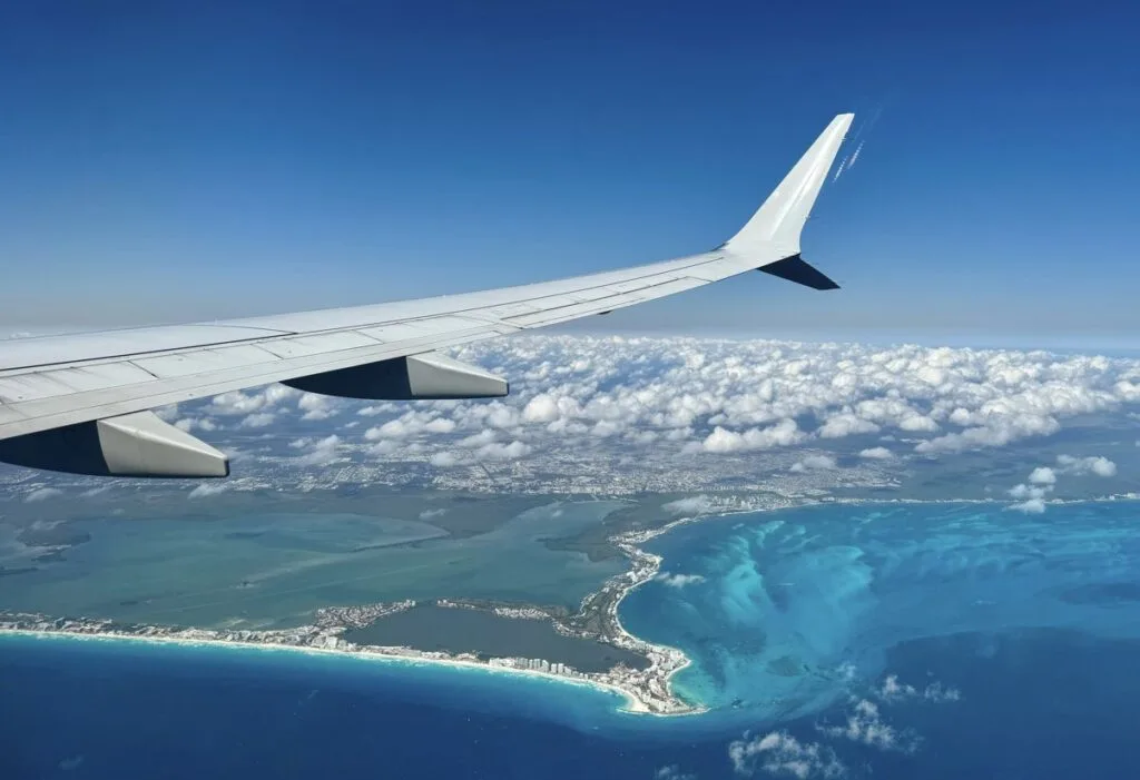 View from airplane window of an airplane wing above the Mexican coastline with the Cancun hotel zone in Quintana Roo, Mexico