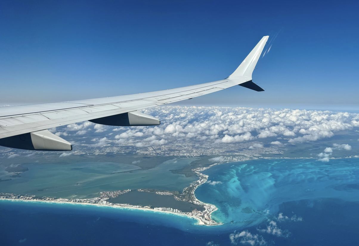 Vista desde la ventana de avión de un ala de avión sobre la costa mexicana con la zona hotelera de Cancún en Quintana Roo, México