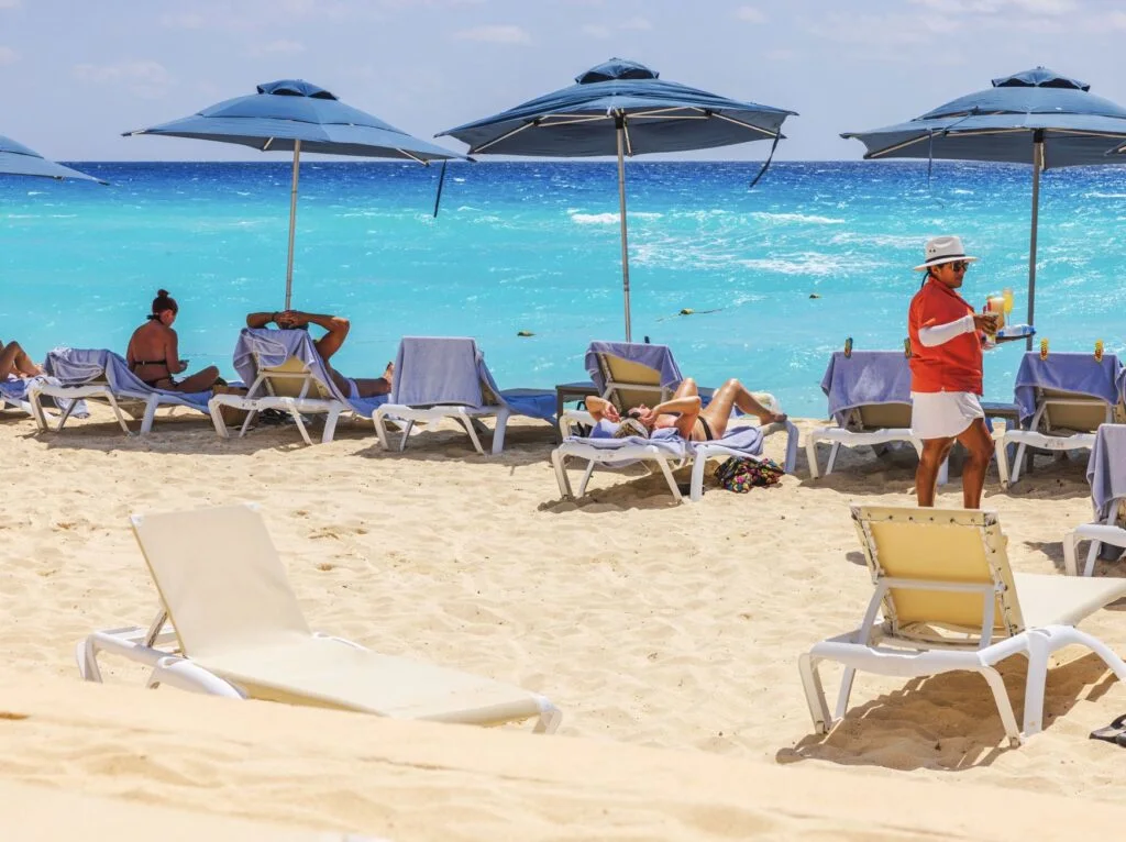 Employee Worker Brings drinsk to tourist on beach in cancun