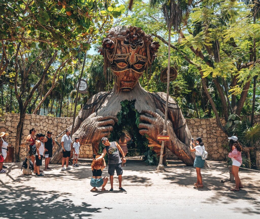 Tourist beachgoers photographing in front of Ven a La luz sculpture installed at the resort Ahau