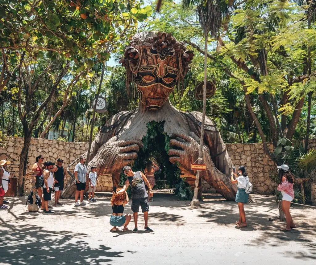 Tourist beachgoers photographing in front of Ven a La luz sculpture installed at the resort Ahau