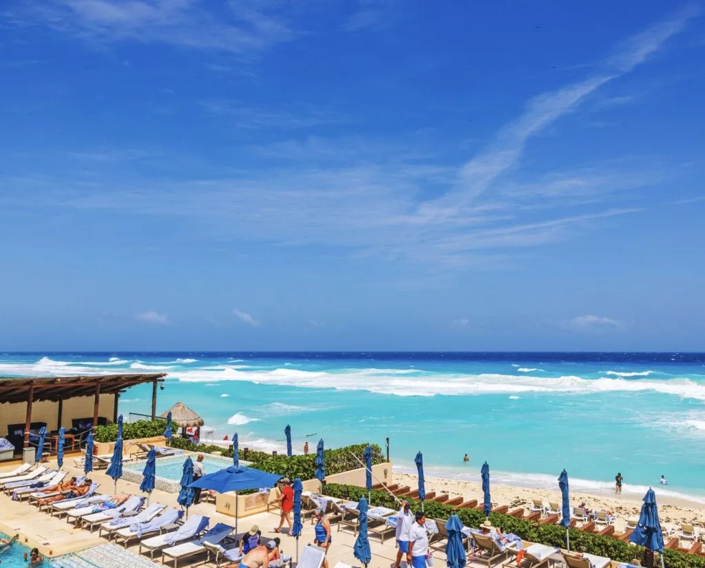 Tourists relax by Pool on beach in Cancun