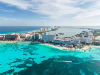 Aerial view of Cancun Hotel Zone with resorts lining the coast on a beautiful day