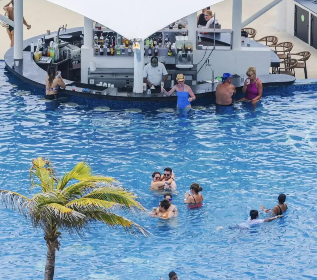 Cancun pool and travelers chatting with bartender