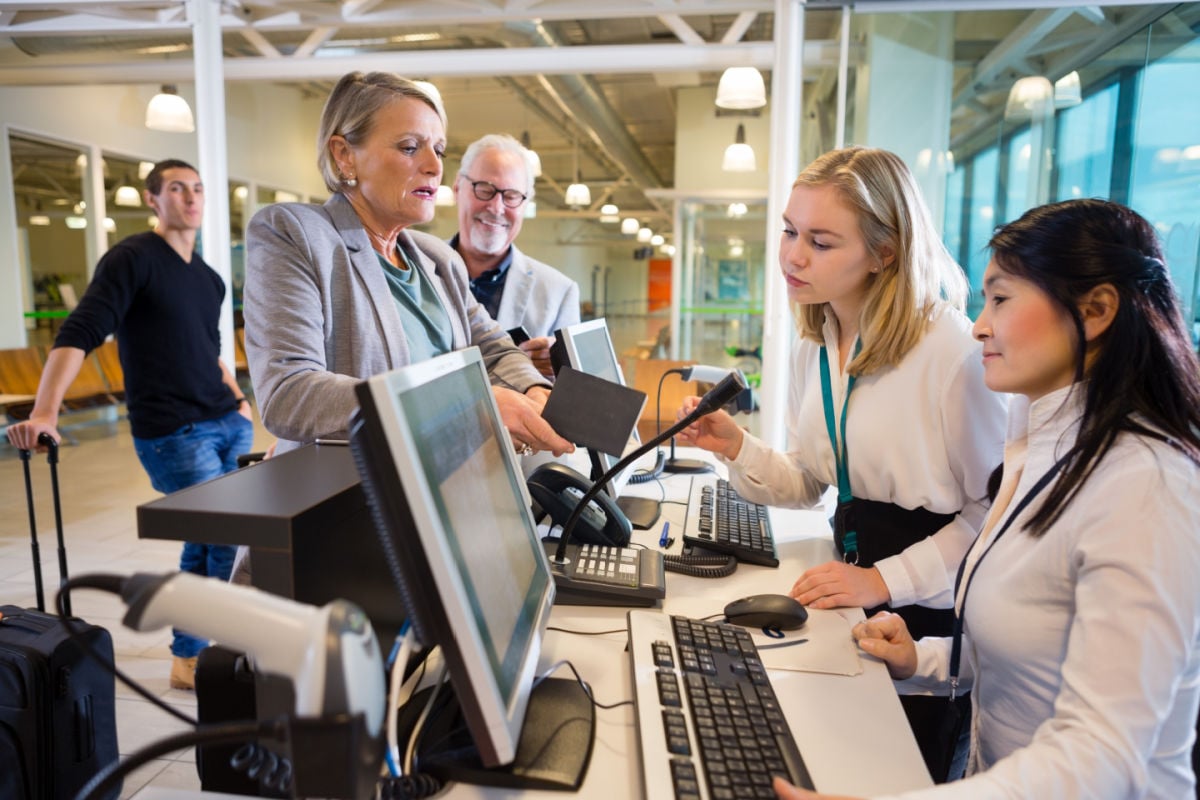 Businesswoman Holding Passport While Staff Working At Airport