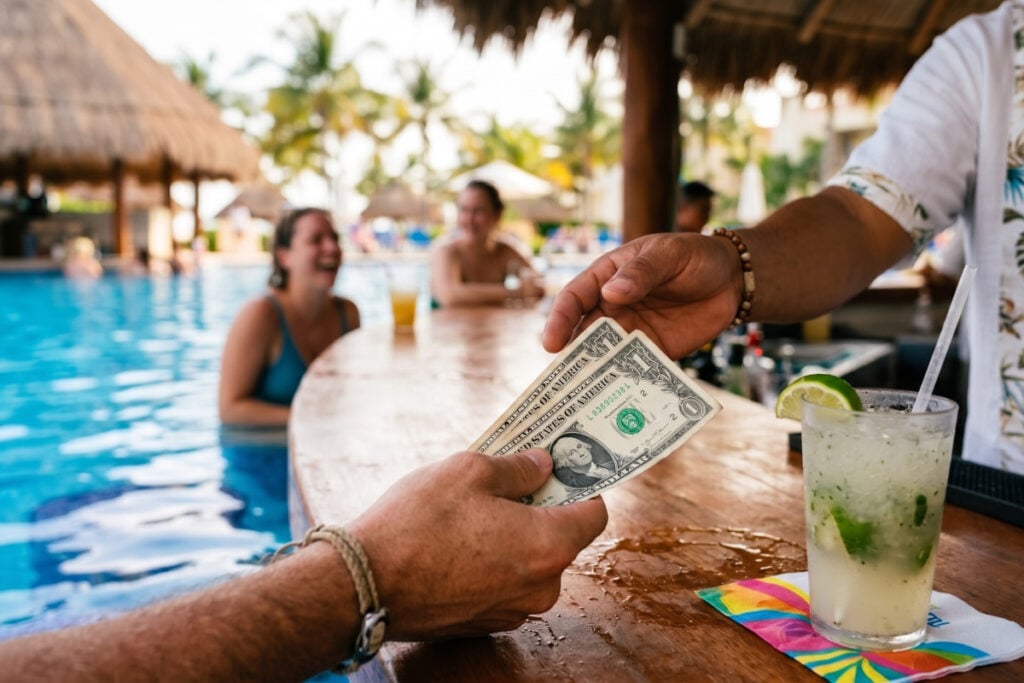 Man handing a bartender dollar bills in cancun