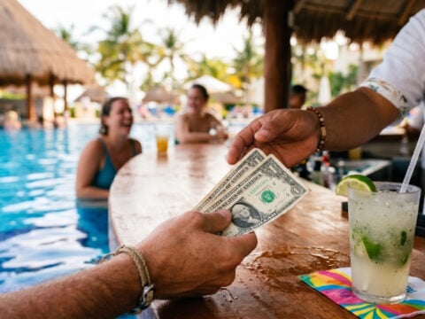 Man handing a bartender dollar bills in cancun