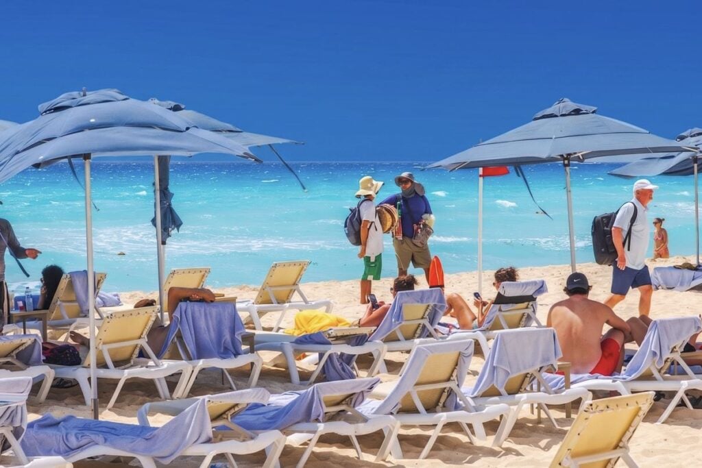 Travelers on beach speaking with vendots