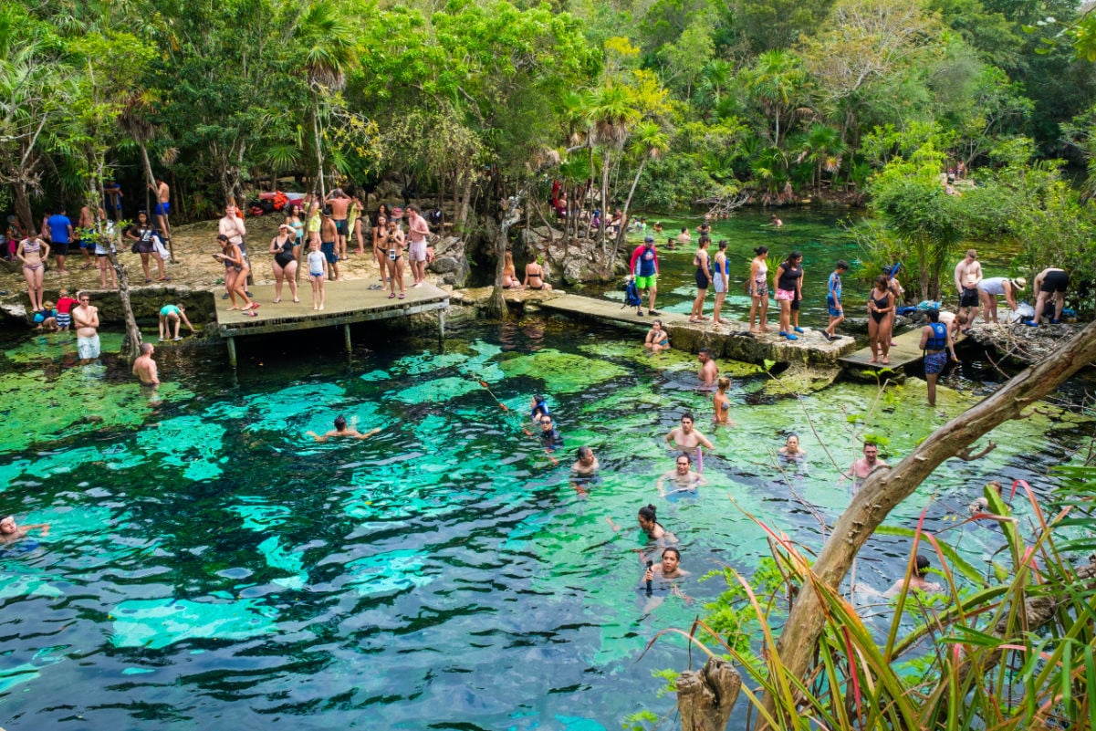 Locals and tourists enjoying an open air cenote at the Yucatan jungle in Mexico