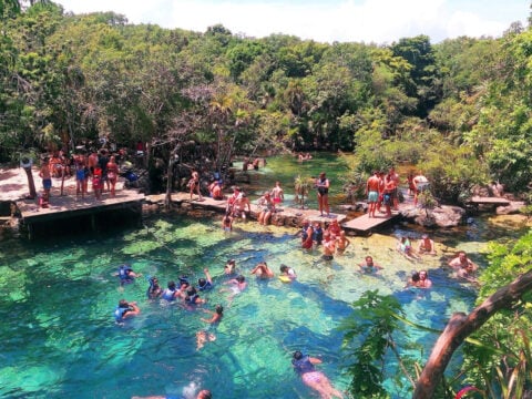 People swimming in crystal clear waters of Cenote Azul, popular natural pool on Riviera Maya in Mexico