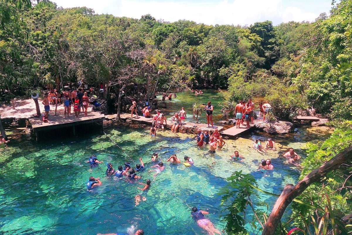 People swimming in crystal clear waters of Cenote Azul, popular natural pool on Riviera Maya in Mexico